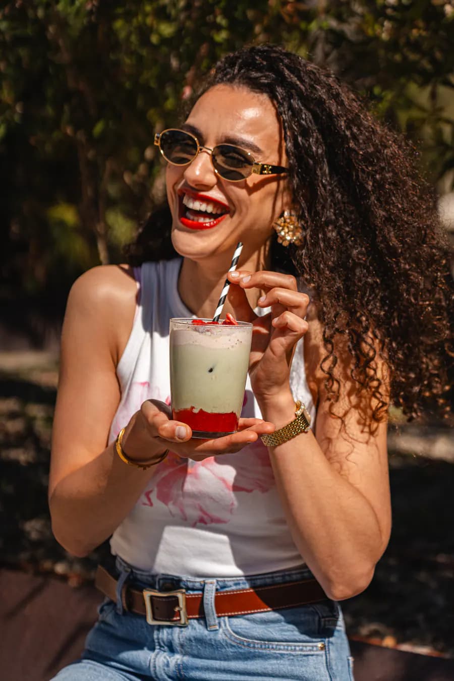 Lachender Gast mit grünem Smoothie im Sommerlicht